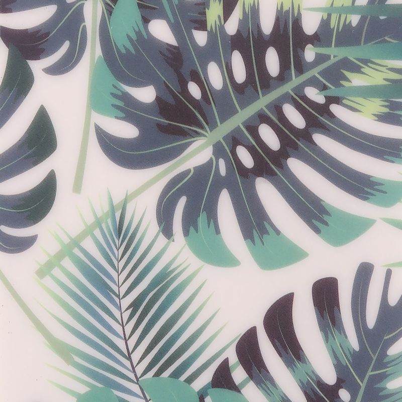 Large printed monstera and palm leaves (teal and dark green with distinctive cutouts) overlapping and covering a white surface â€” decorative pattern, close-up, evenly lit.
