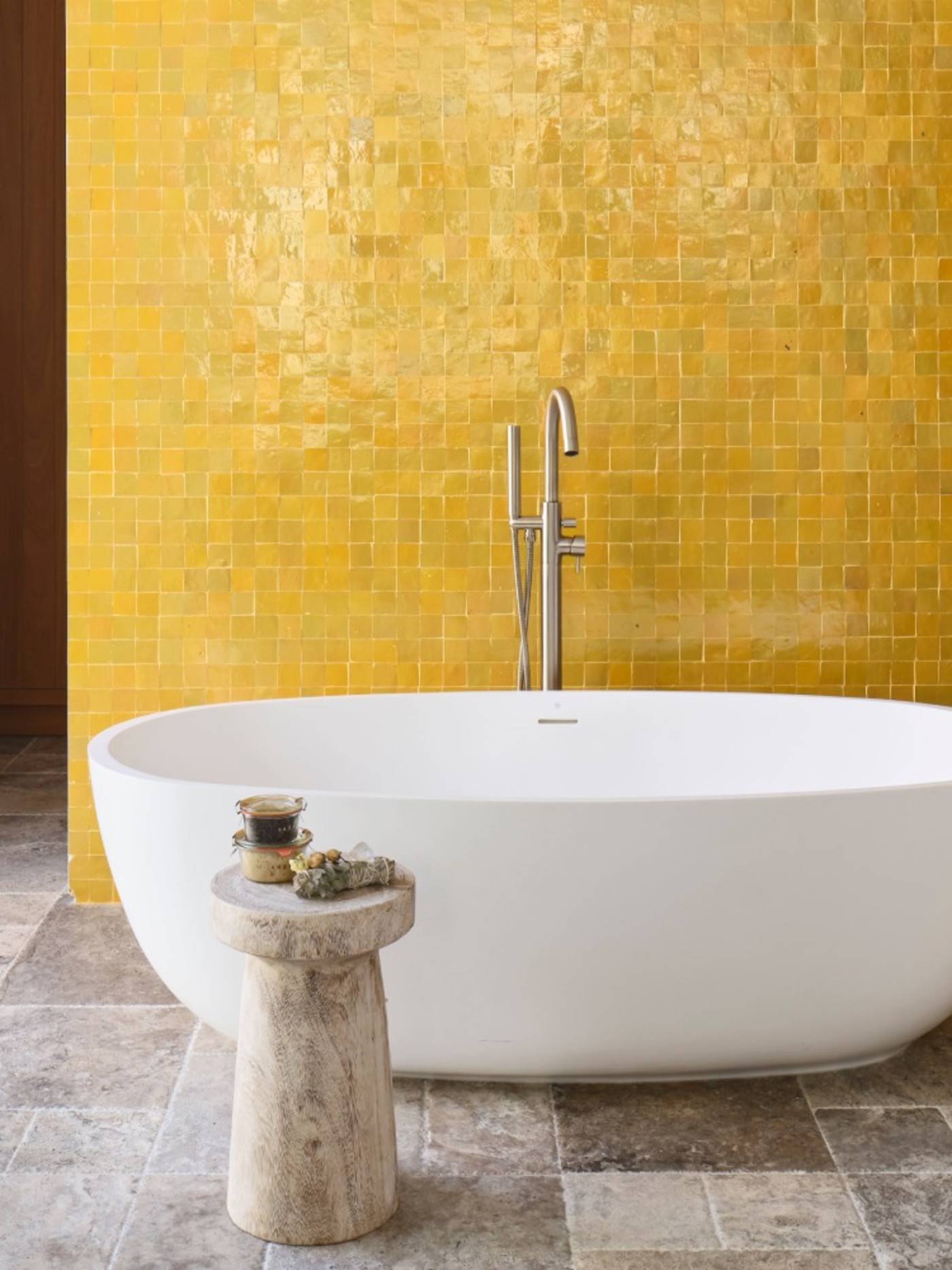 a bathtub in front of a yellow tiled wall.