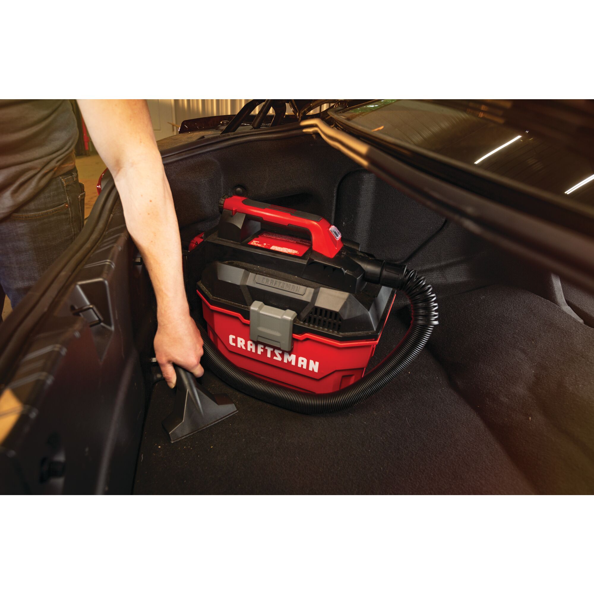20 volt cordless 2 gallon wet dry vacuum being used by a person to clean car trunk.