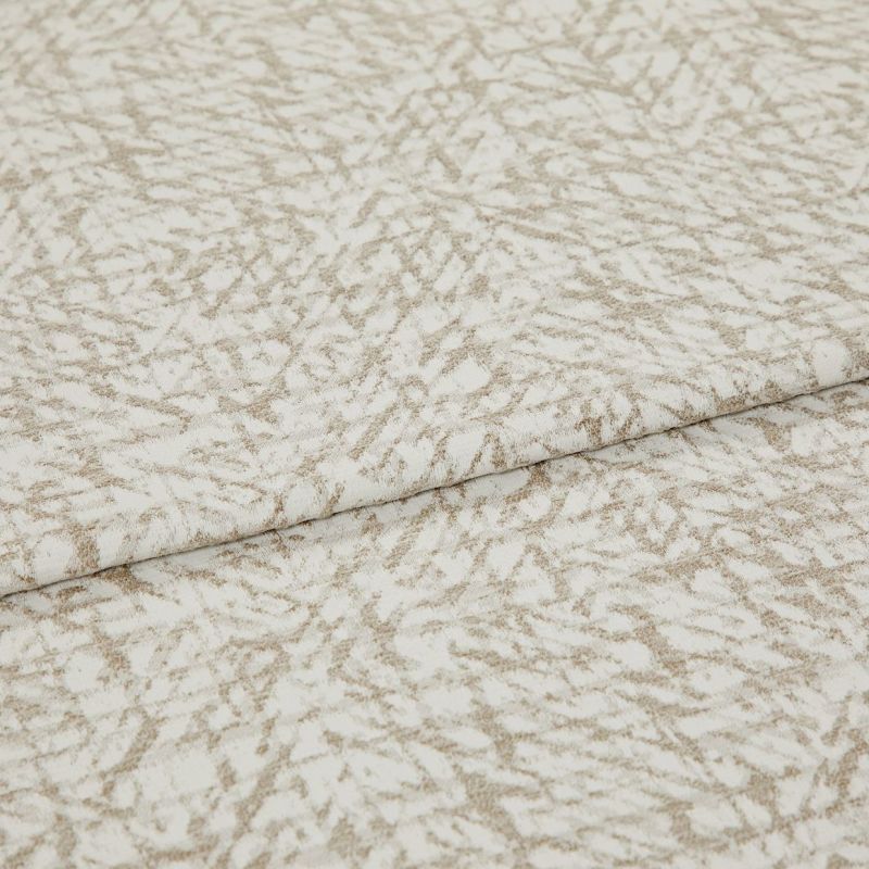 Textured beige-and-white fabric with an abstract, twiglike pattern, folded and layered once; close-up on a flat surface with soft, even lighting, suggesting a fabric sample or upholstery swatch.