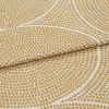 Cream woven fabric with raised golden-dot concentric pattern, folded and slightly overlapped, shown in a close-up with soft, even lighting and shallow depth of field.