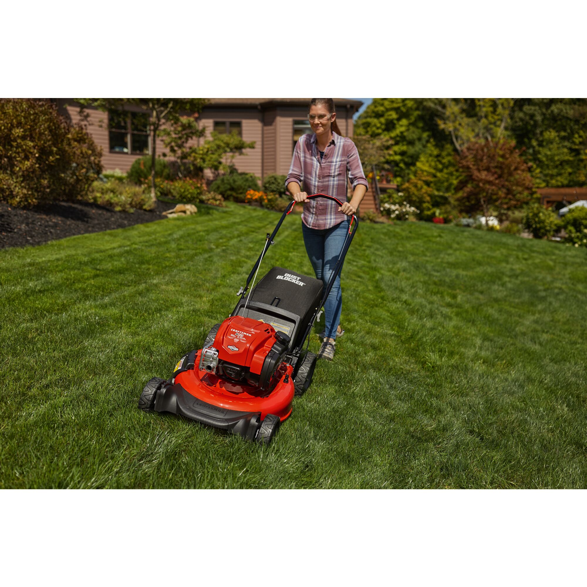 CRAFTSMAN M125 Push Mower mowing the grass in the backyard in front view in plaid shirt