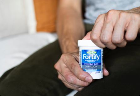 A man opening a bottle of Fortify Men’s Daily Probiotic.