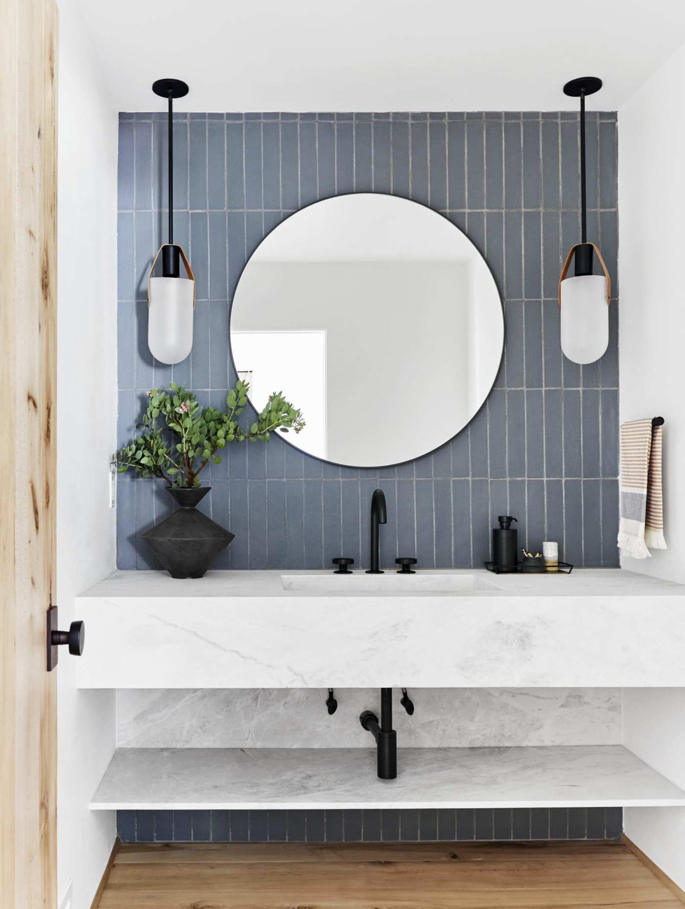 a bathroom with blue walls and a round mirror.