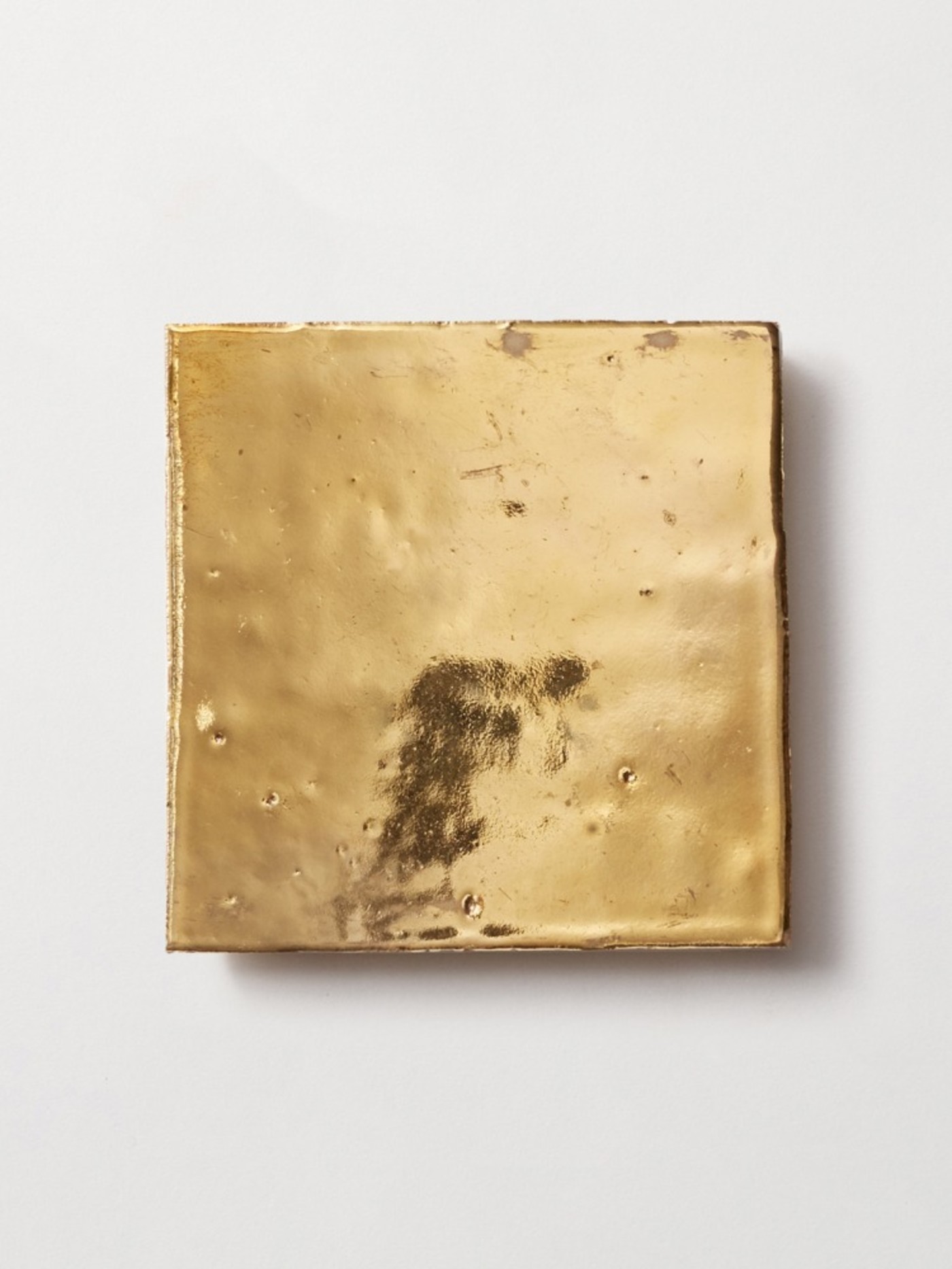 a gold square tile on a white surface.