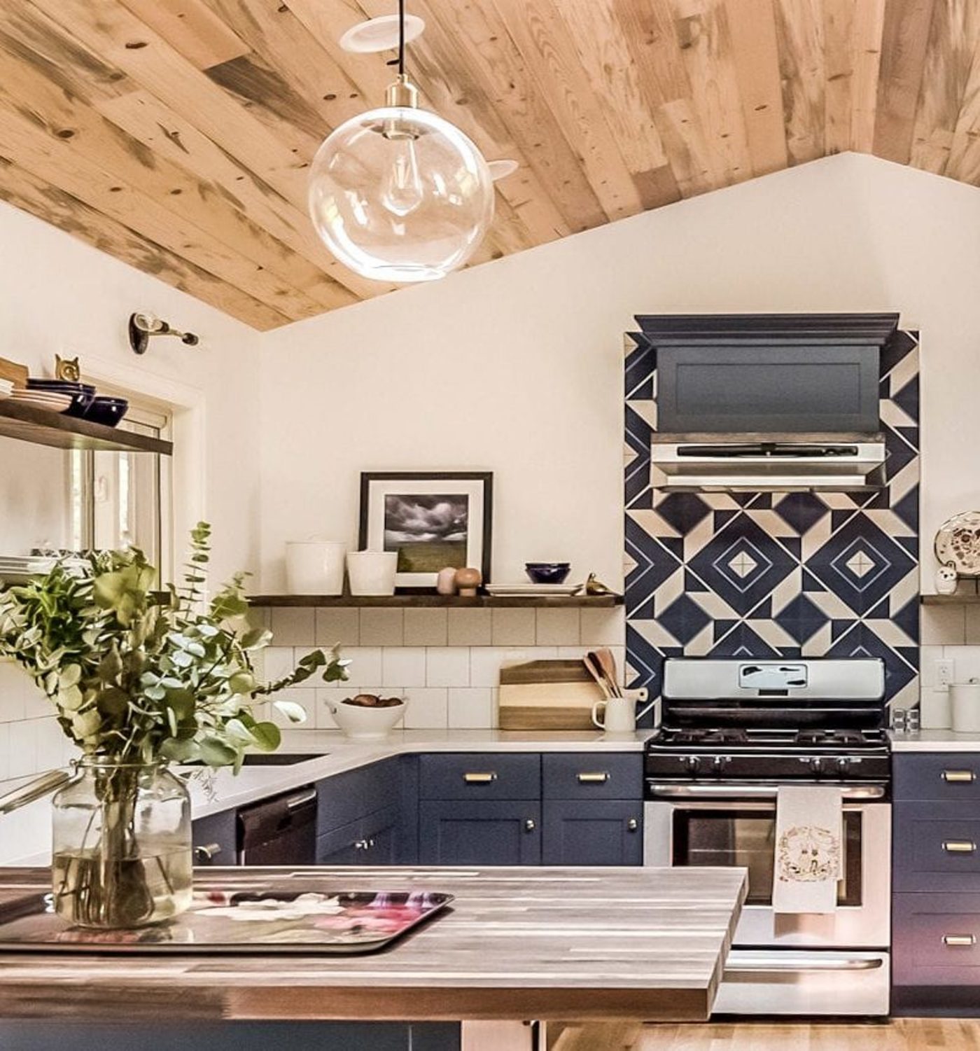 a blue and white kitchen with a wooden ceiling.