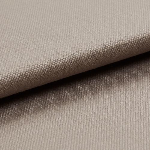 Beige tightly woven upholstery fabric, folded with an overlapping edge across the frame, revealing a pebble-like weave; close-up macro view with soft neutral lighting and plain background.