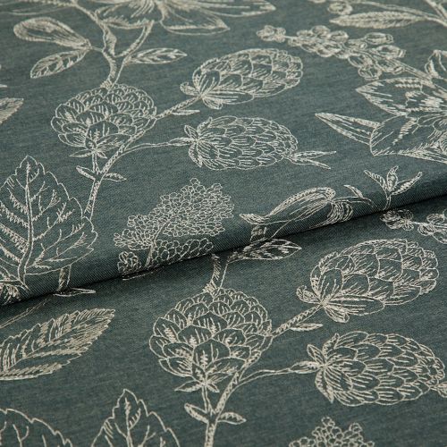 Dark teal fabric with white stitched botanical motifs (artichoke-like blooms and leaves), folded across the center, displaying layered, textured weave under soft, neutral studio lighting.