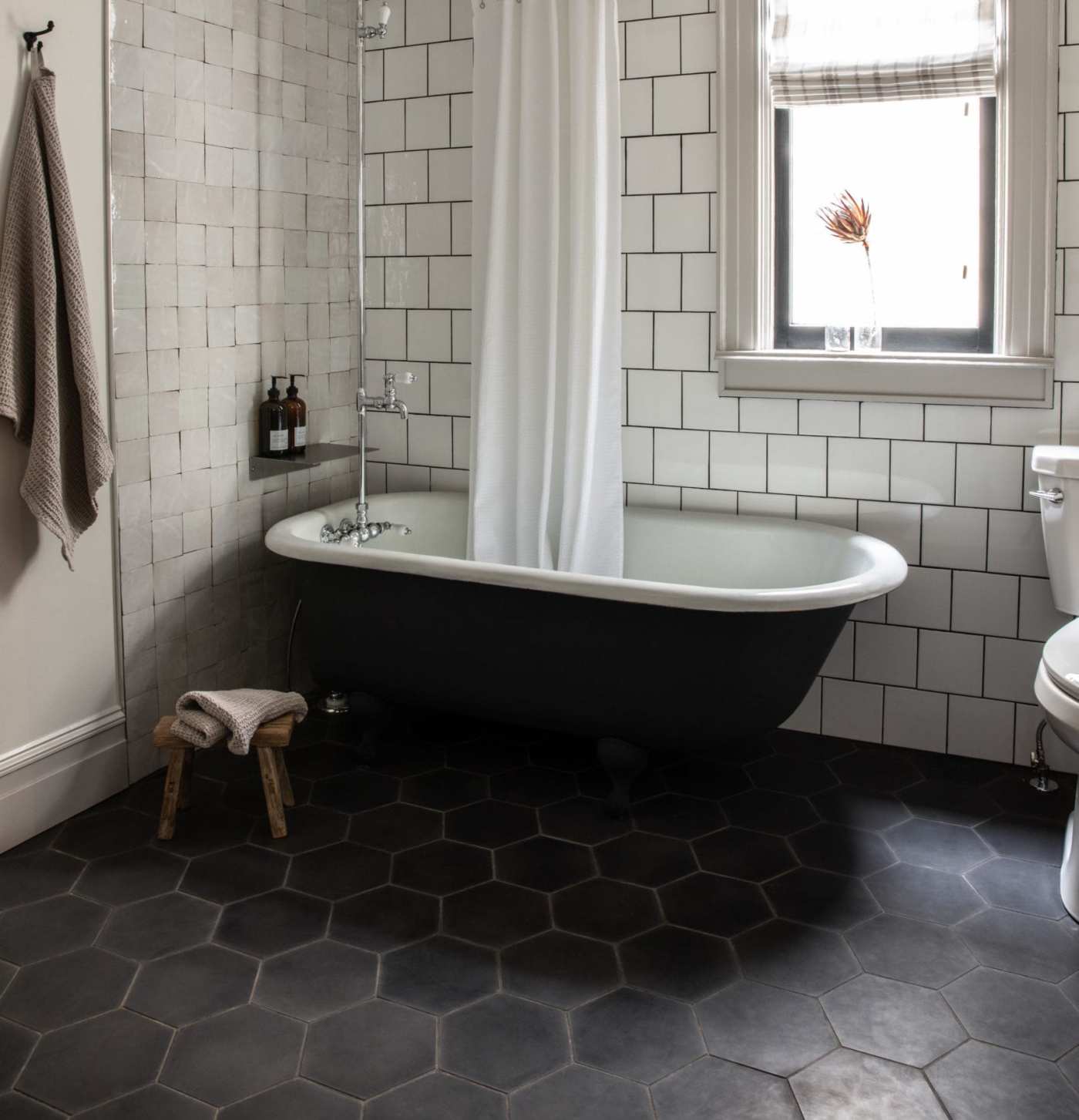 a bathroom with a black tile floor, bathtub and white tiled walls.