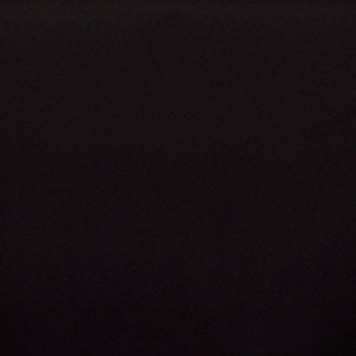 Matte dark wall centered in frame, flat and featureless; absorbing light and appearing unlit; context: dim indoor scene with no visible details or furnishings.