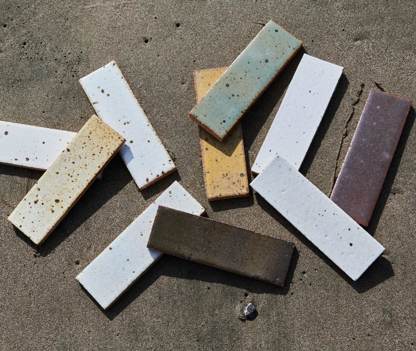 a group of different colored tiles laying on the sand.