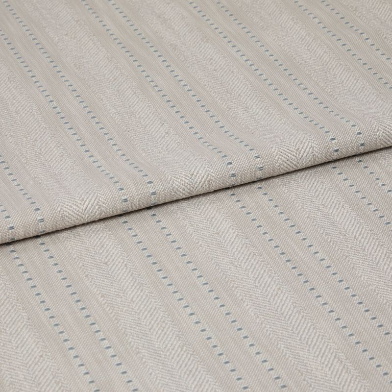 Beige woven fabric featuring herringbone chevrons and thin blue dotted vertical stripes â€” folded over itself, displayed as a close-up textile sample on a neutral, softly lit surface.
