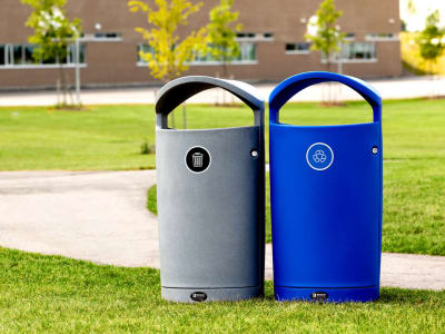 grey waste and blue recycling bins outdoors in high school yard