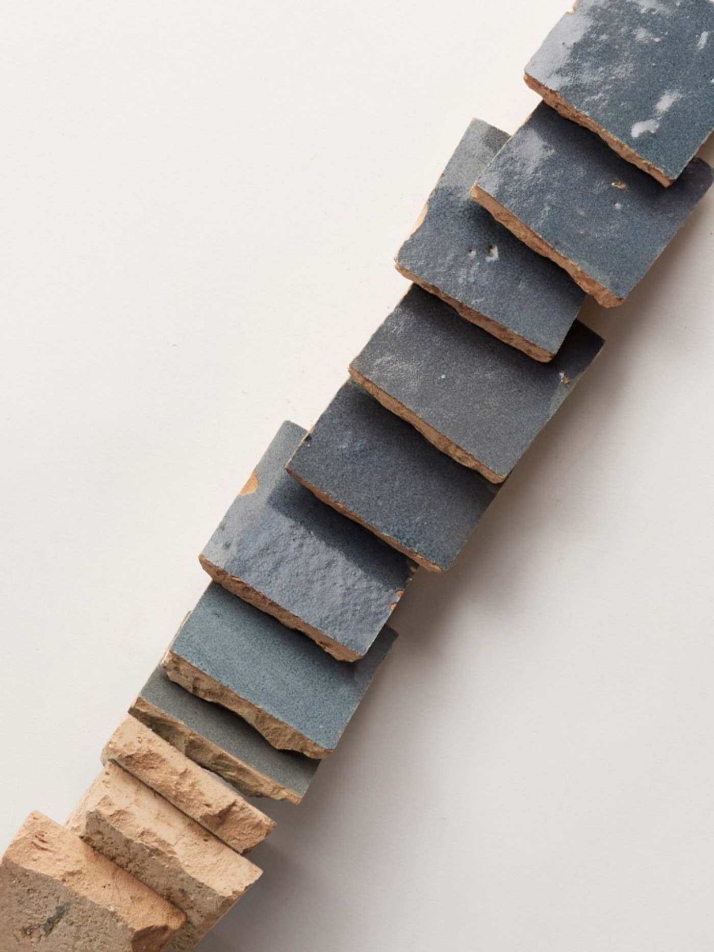 a stack of grey tiles on a white surface.