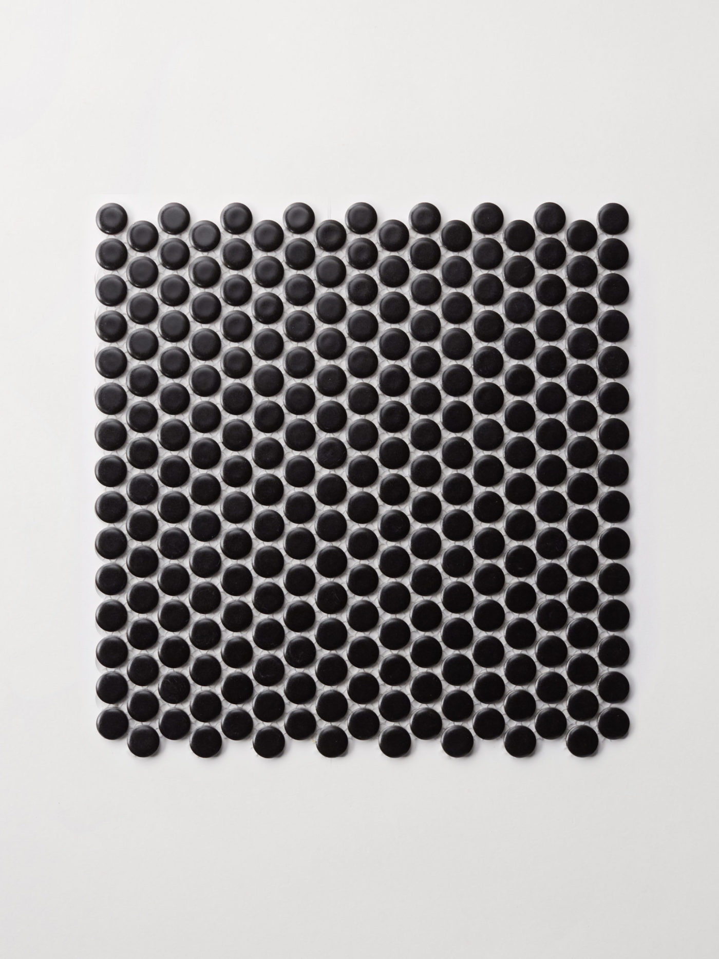 black, round mosiac tile on a white surface.