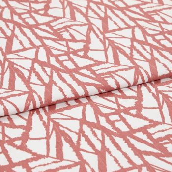 White fabric with coral-pink angular, brushlike linear pattern, folded over itself; fabric lies flat, close-up studio view showing texture and repeating print.