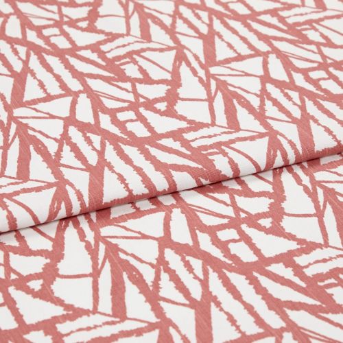 White fabric with coral-pink angular, brushlike linear pattern, folded over itself; fabric lies flat, close-up studio view showing texture and repeating print.