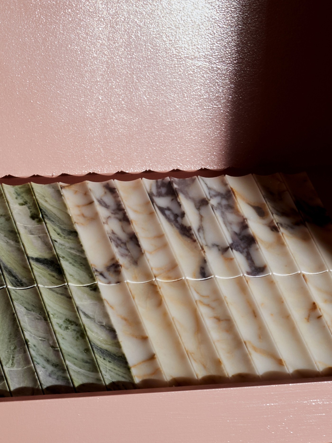 a row of marble soaps on a pink shelf.