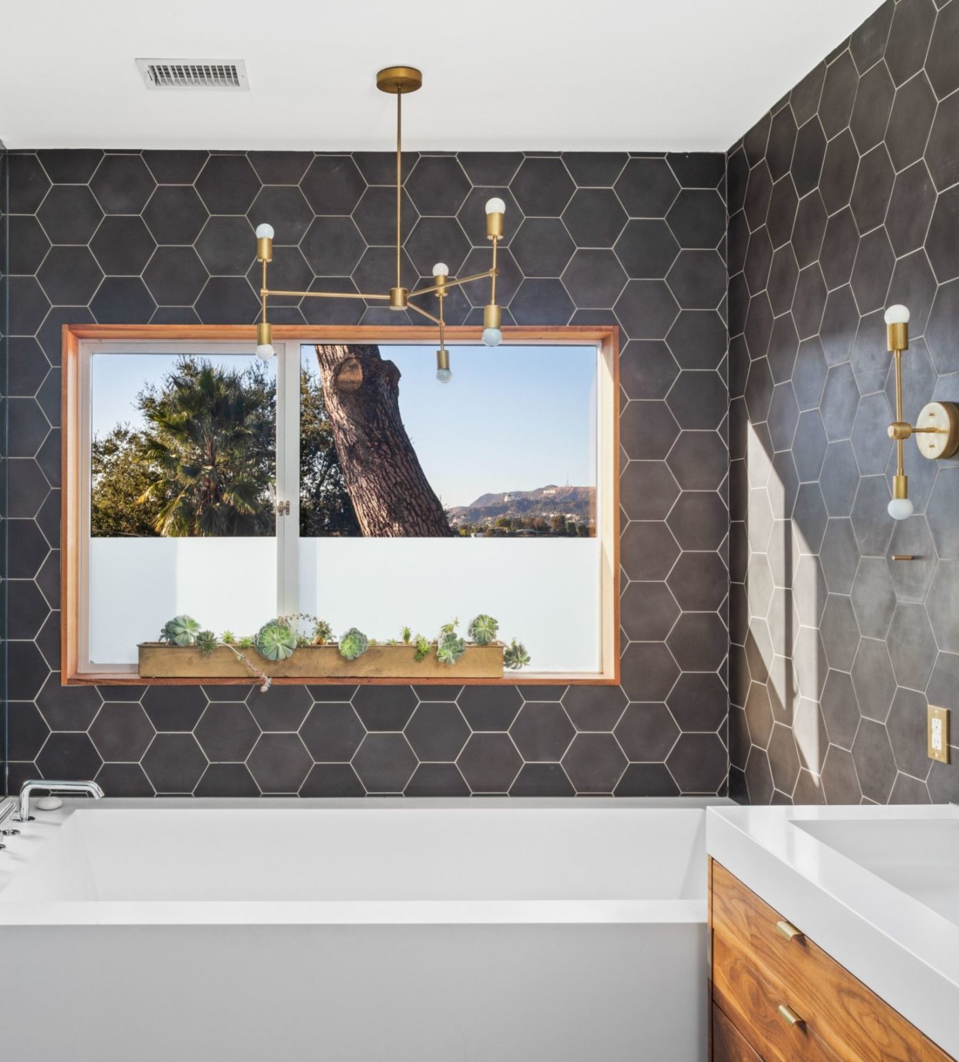 a bathroom with black hexagon tile walls and a window.