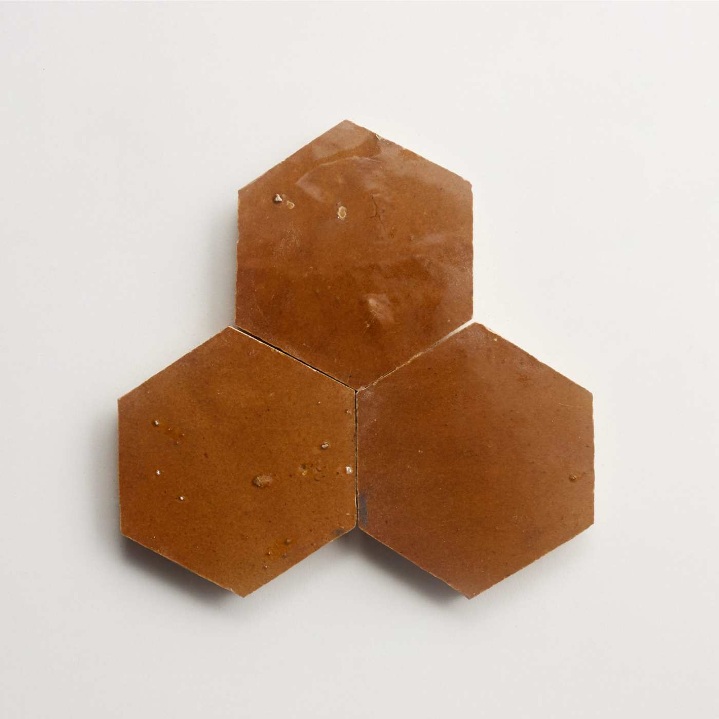 three brown hexagon tiles on a white surface.