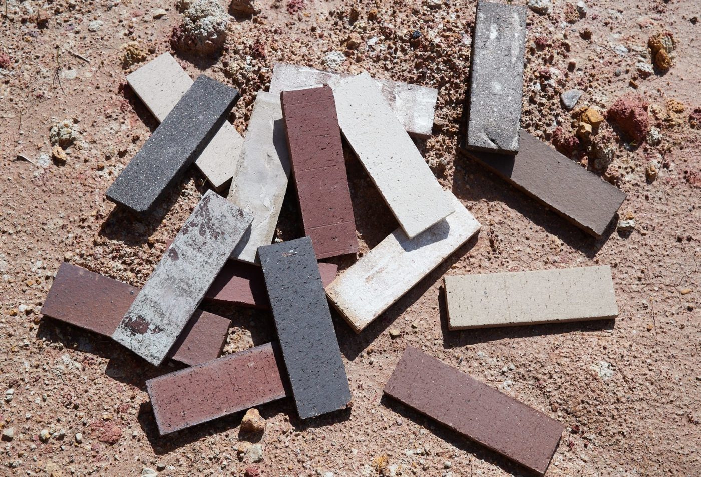 a group of multicolored bricks scattered in the sand.