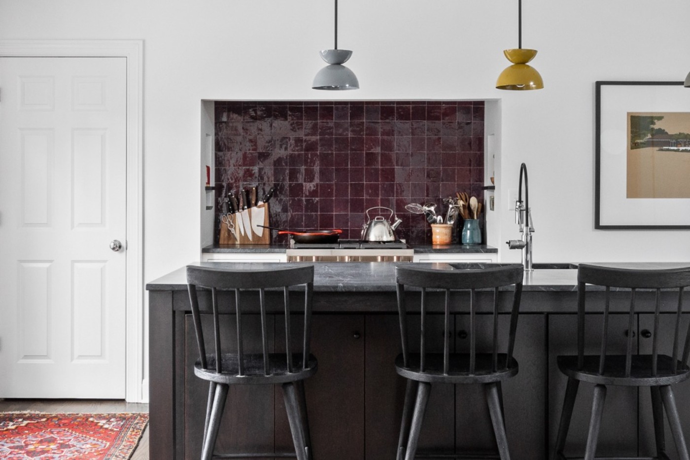 a kitchen with black stools and a tiled backsplash.