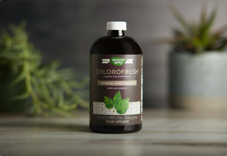 A bottle of Chlorofresh sitting on a table with plants in the background.