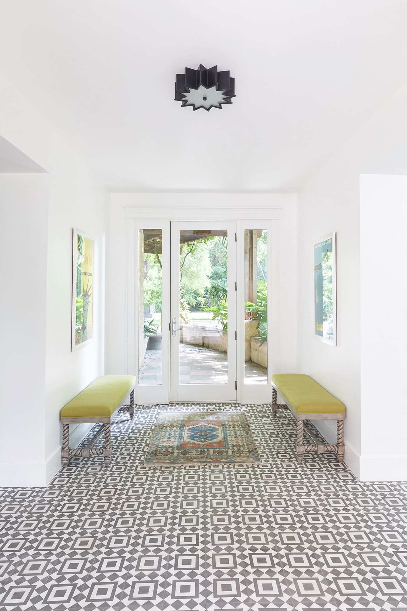 an entryway with a black and white tiled floor and a bench.