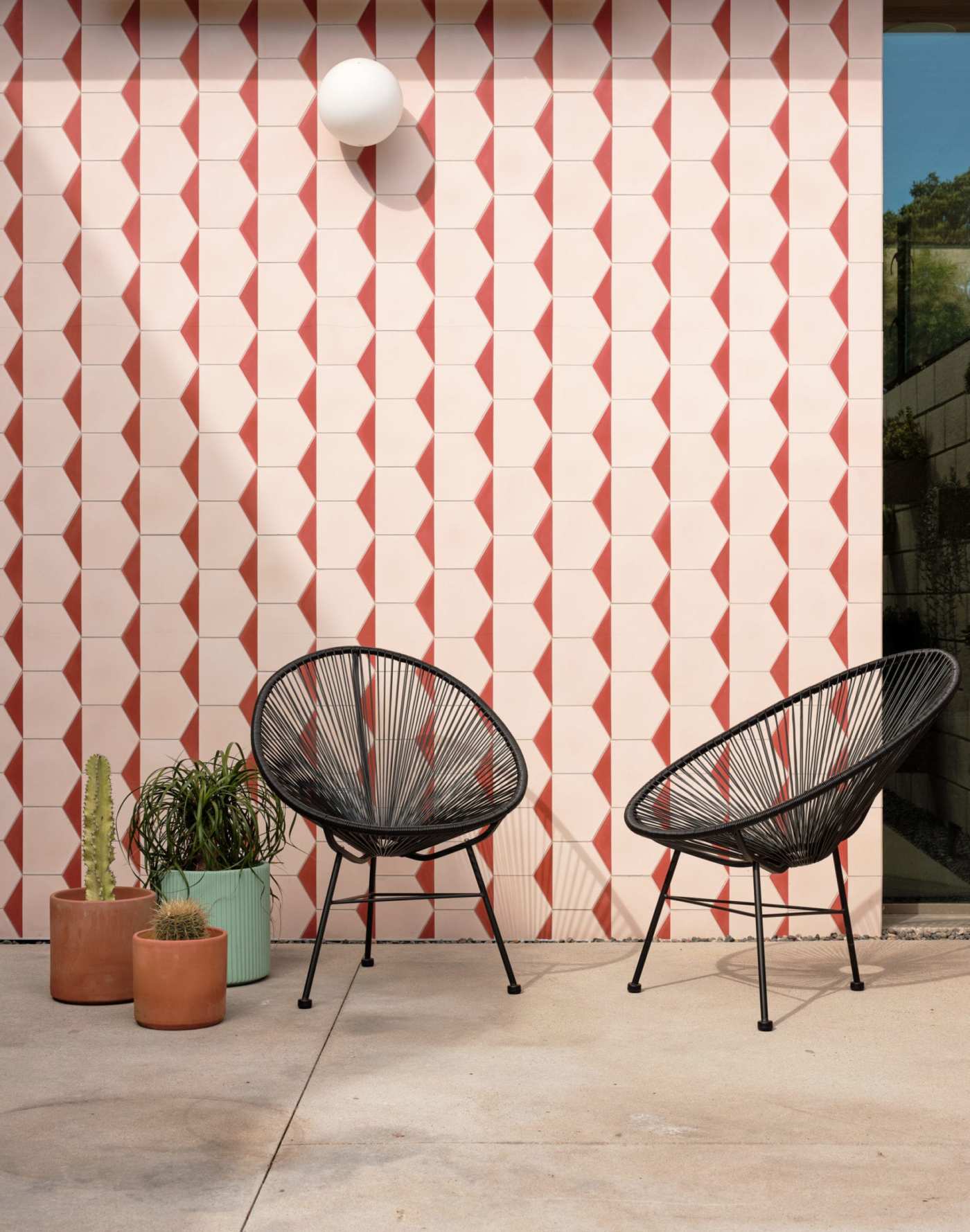 two chairs in front of a pink and red tiled wall.