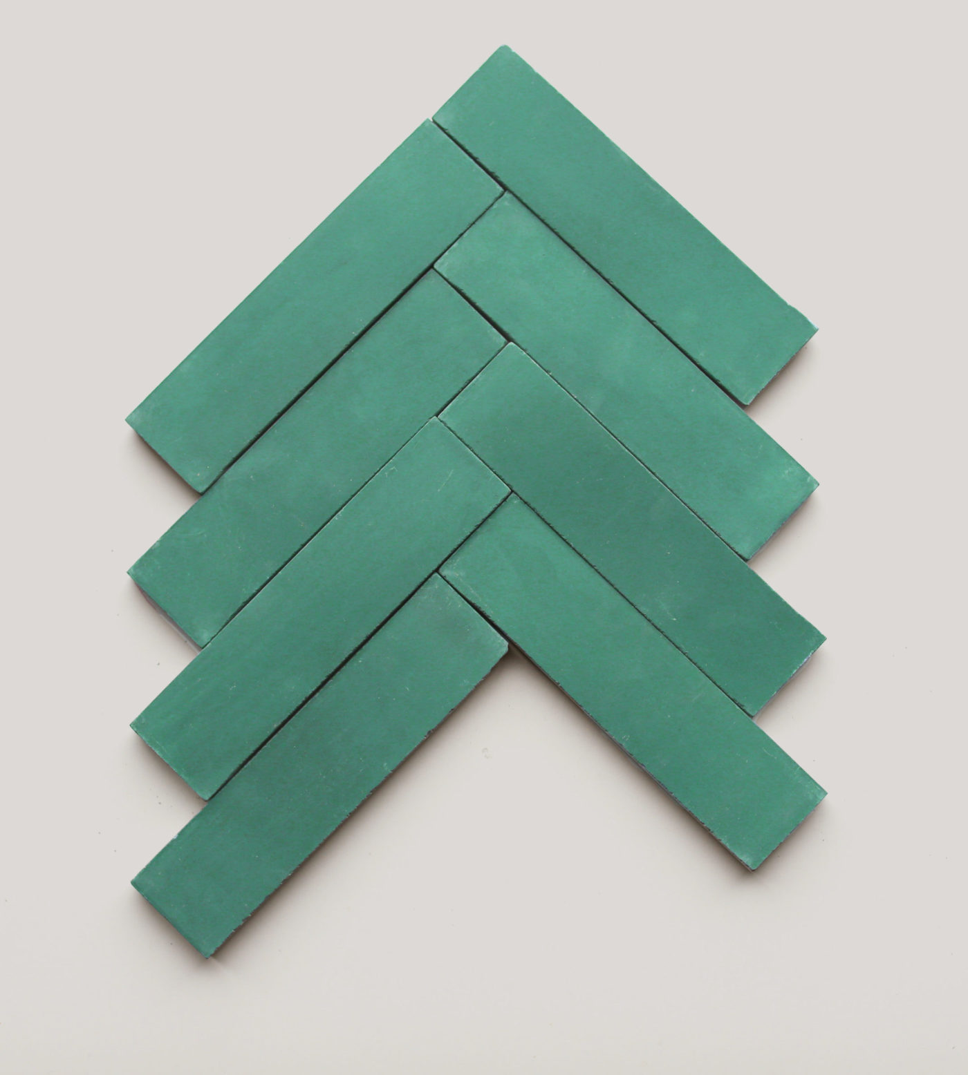 a set of green tiles in a herringbone pattern on a white background.