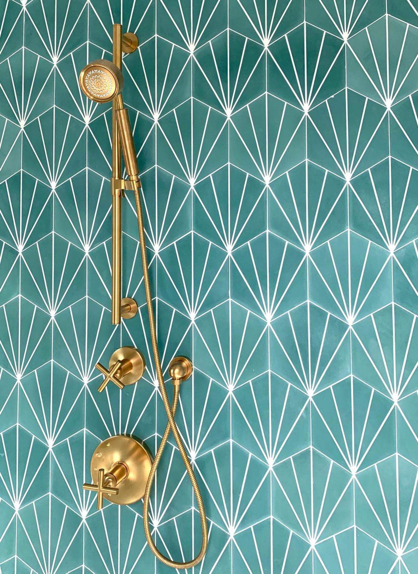 a bathroom with a gold shower head and green tile.