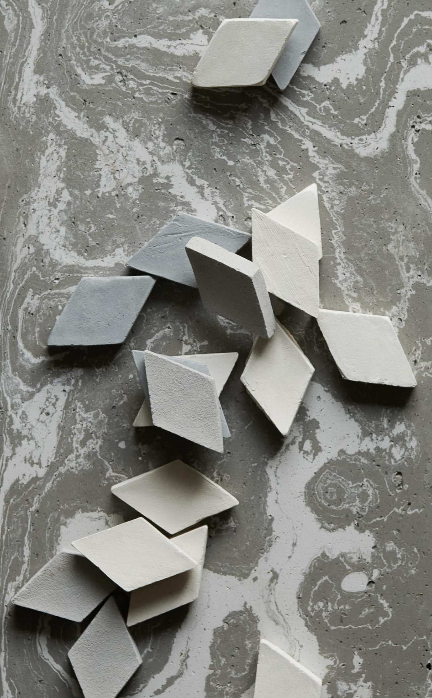 a group of small grey diamond tiles on a grey and white surface.