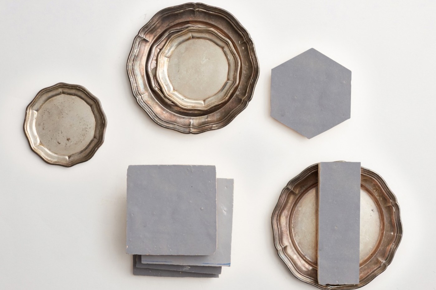 grey tiles and silver plates on a white surface.