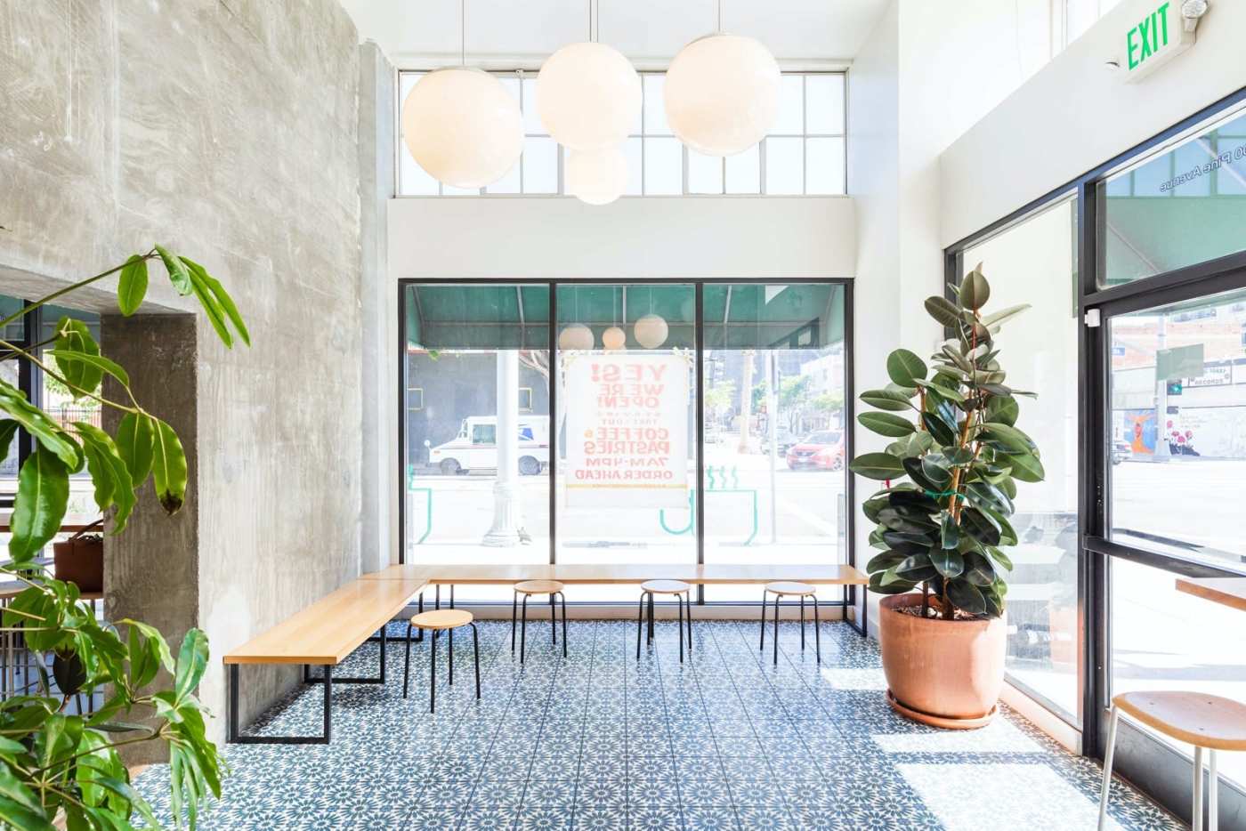 the interior of a coffee shop with benches and potted plants.