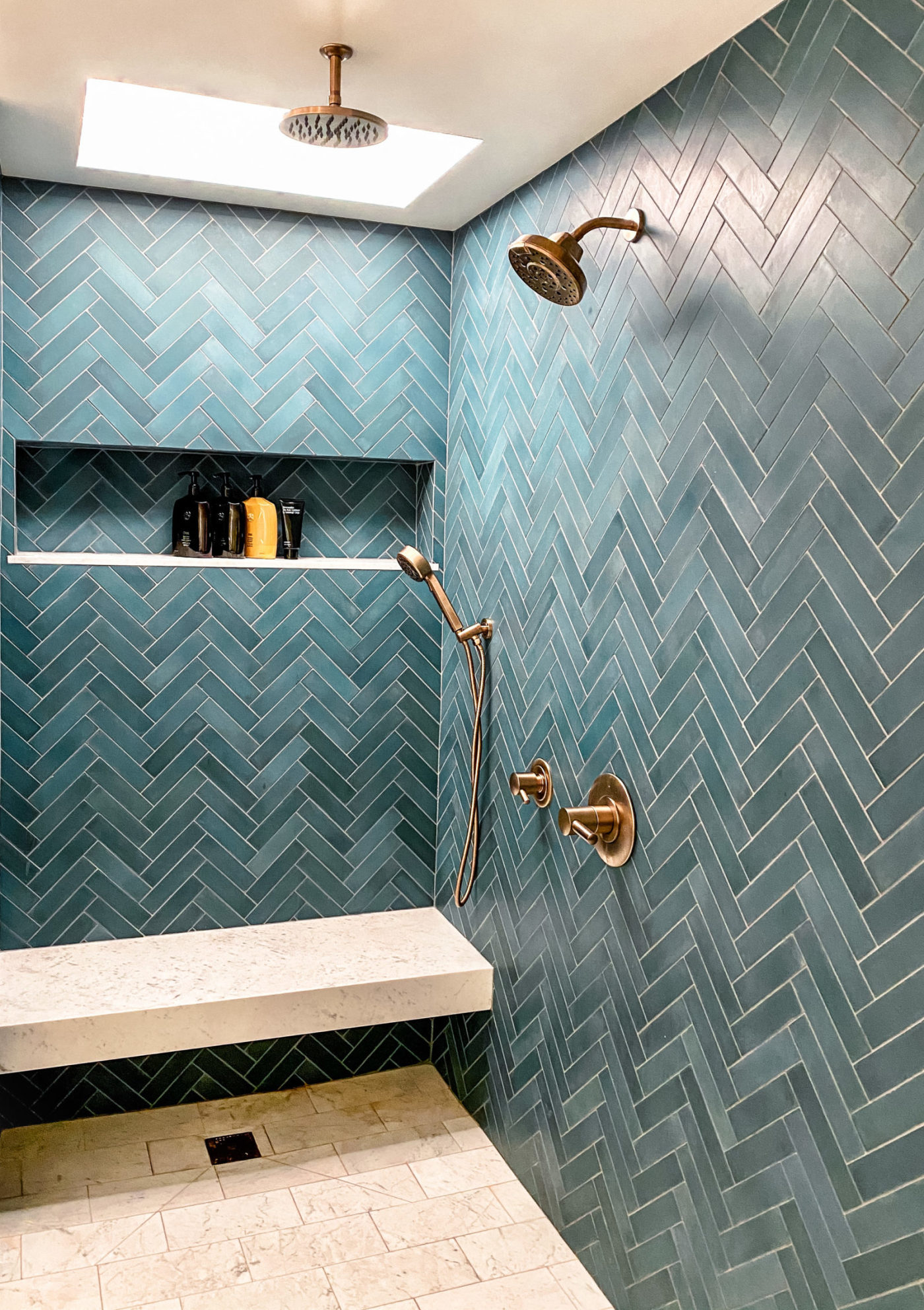 a blue tiled shower with a bench and shower head.