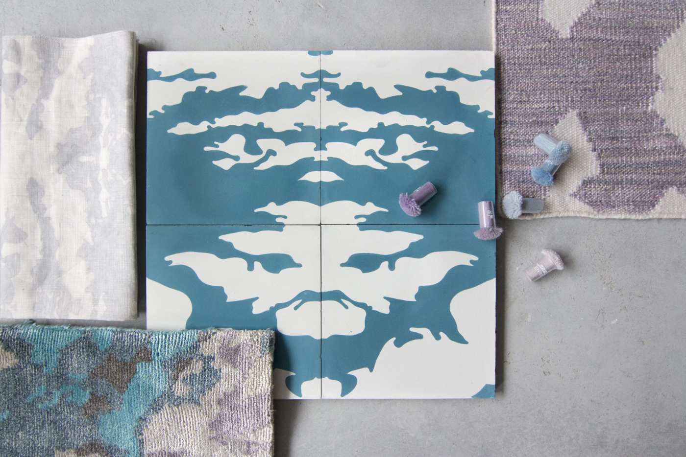 four blue and white patterned tiles on a grey surface.