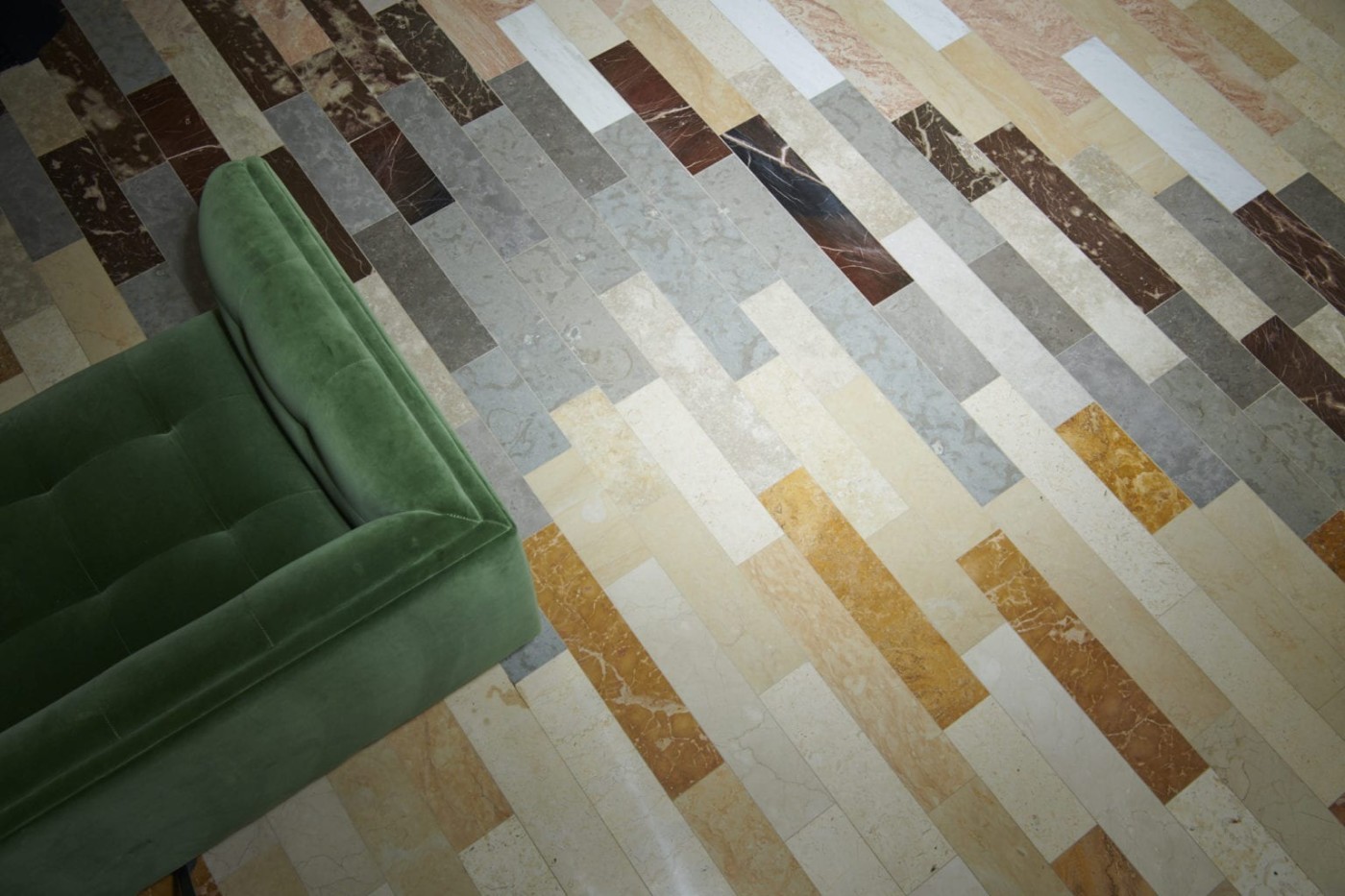 a green chair is sitting on a tile floor.