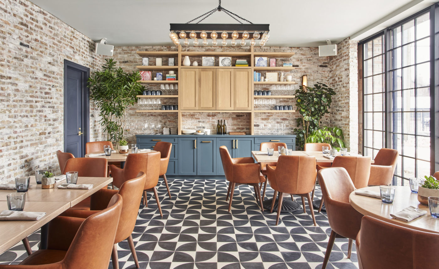 the interior of a restaurant with brick walls and a tiled floor.