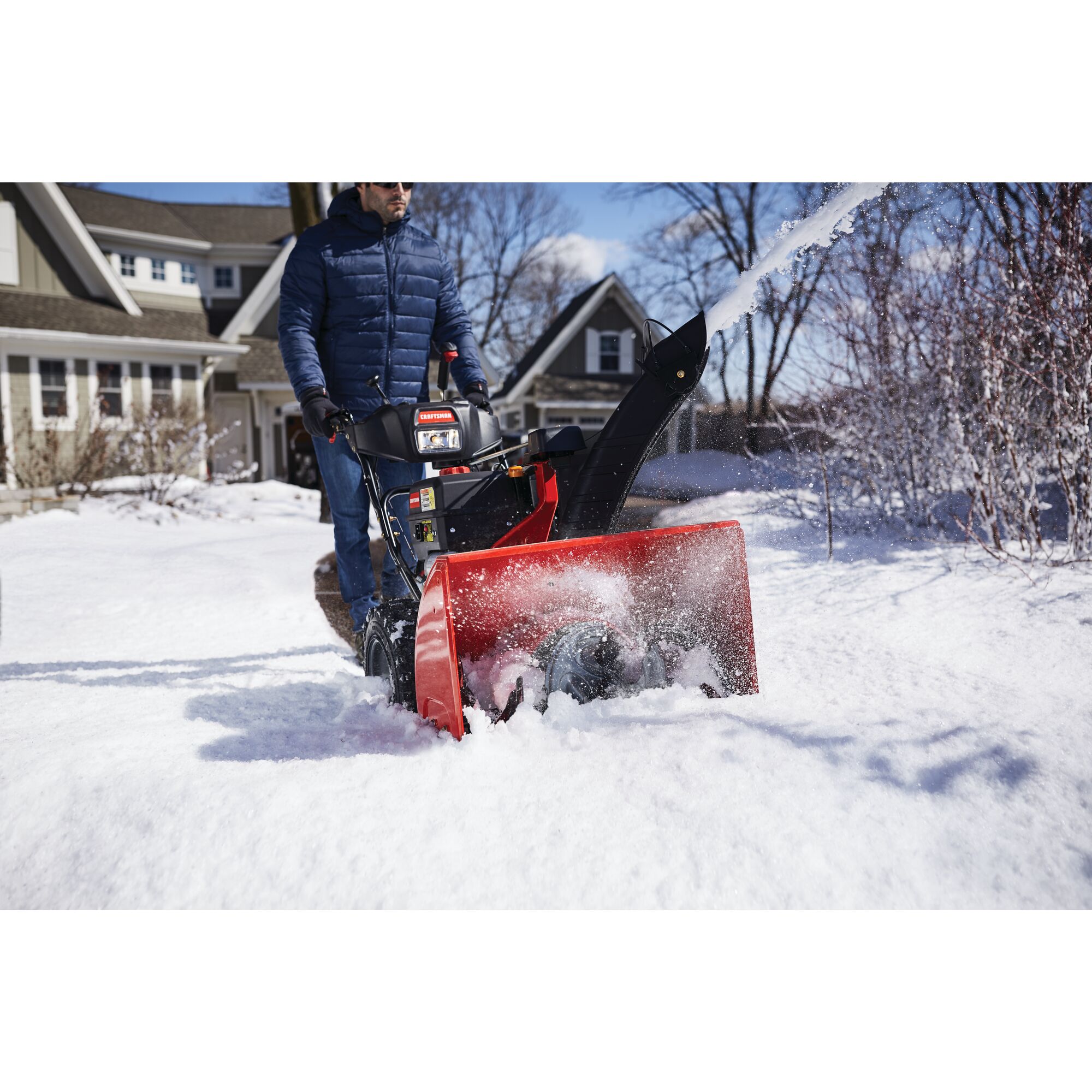 CRAFTSMAN Electric Start 3-Stage Snow Blower blowing the snow in a yard in front view in blue jacket