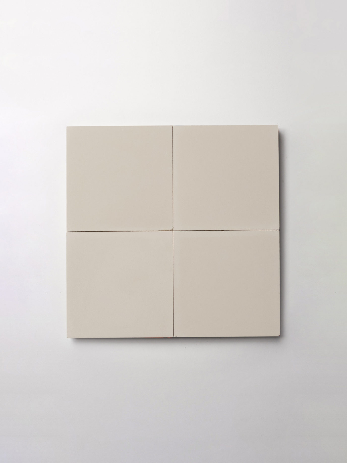 four square beige tiles on a white surface.