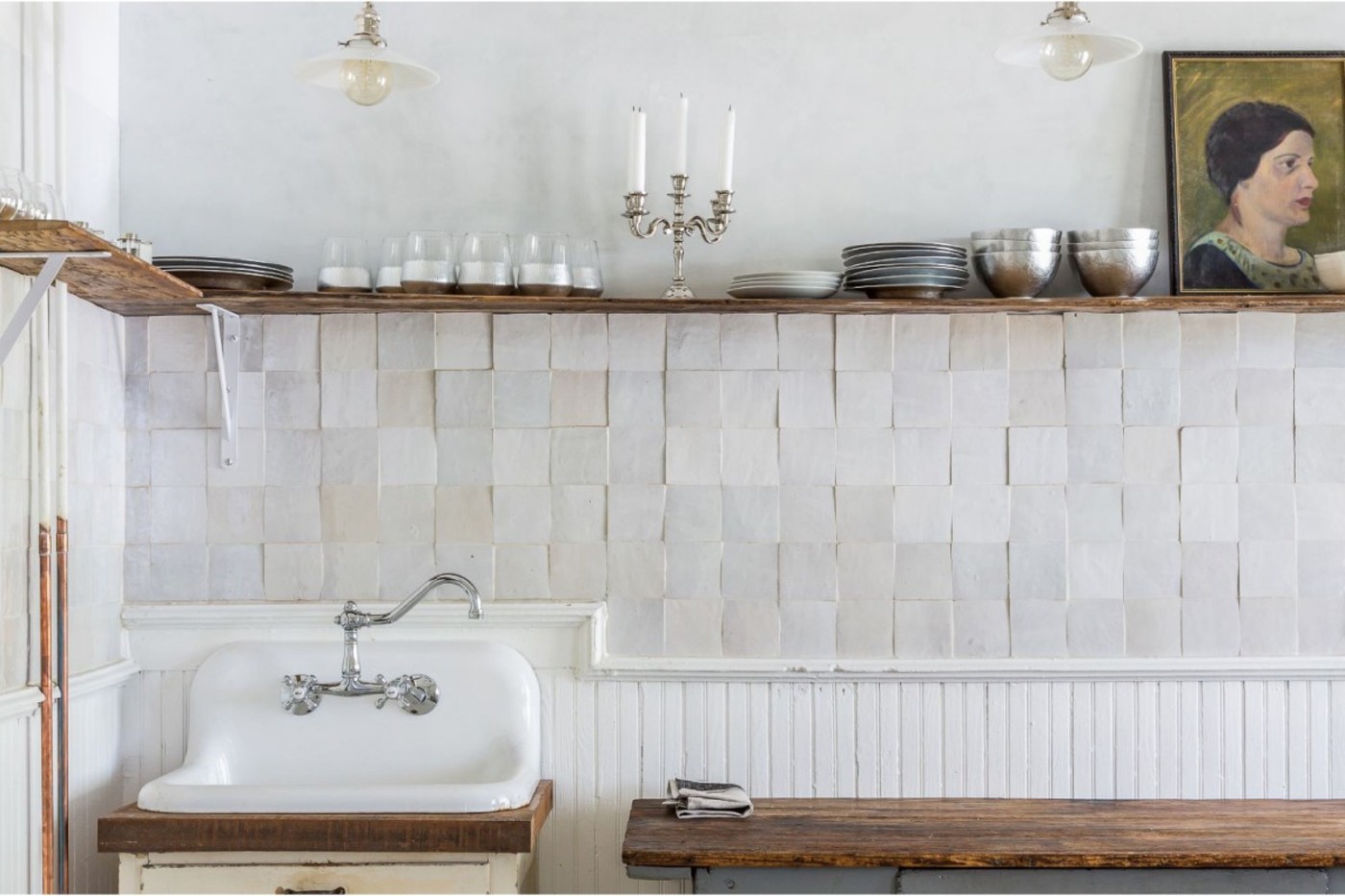 a country kitchen with a wooden counter, a sink and white tile backsplash.