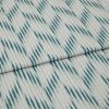 Folded woven fabric with teal ikat-like diagonal stripes and subtle vertical ribbing â€” folded once, lying flat on a neutral surface, close-up, soft even lighting.