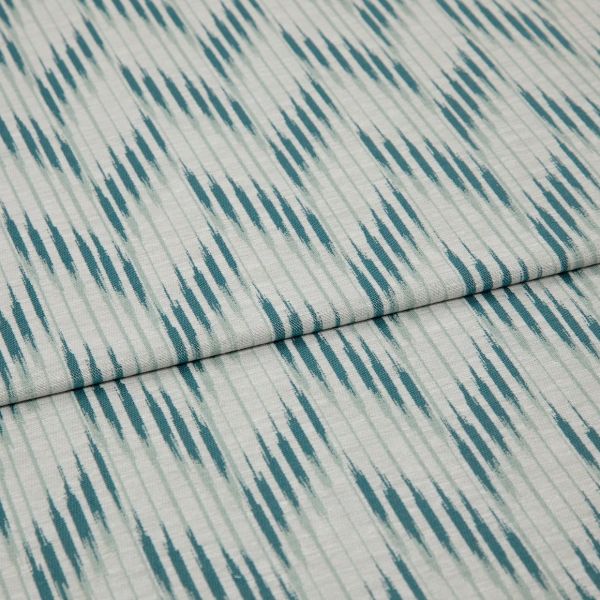 Folded woven fabric with teal ikat-like diagonal stripes and subtle vertical ribbing — folded once, lying flat on a neutral surface, close-up, soft even lighting.