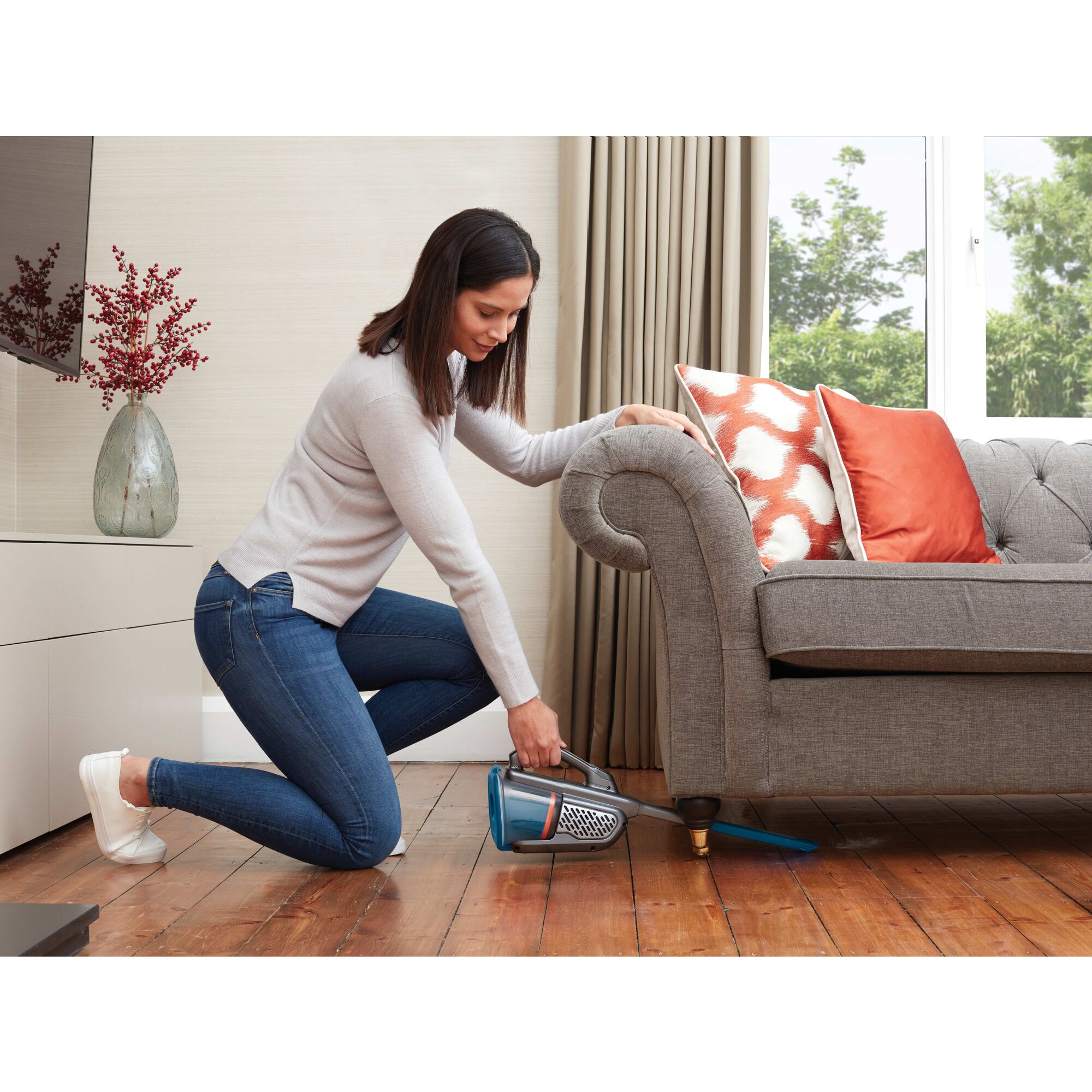 12 volt dustbuster advanced clean cordless hand vacuum being used under sofa.