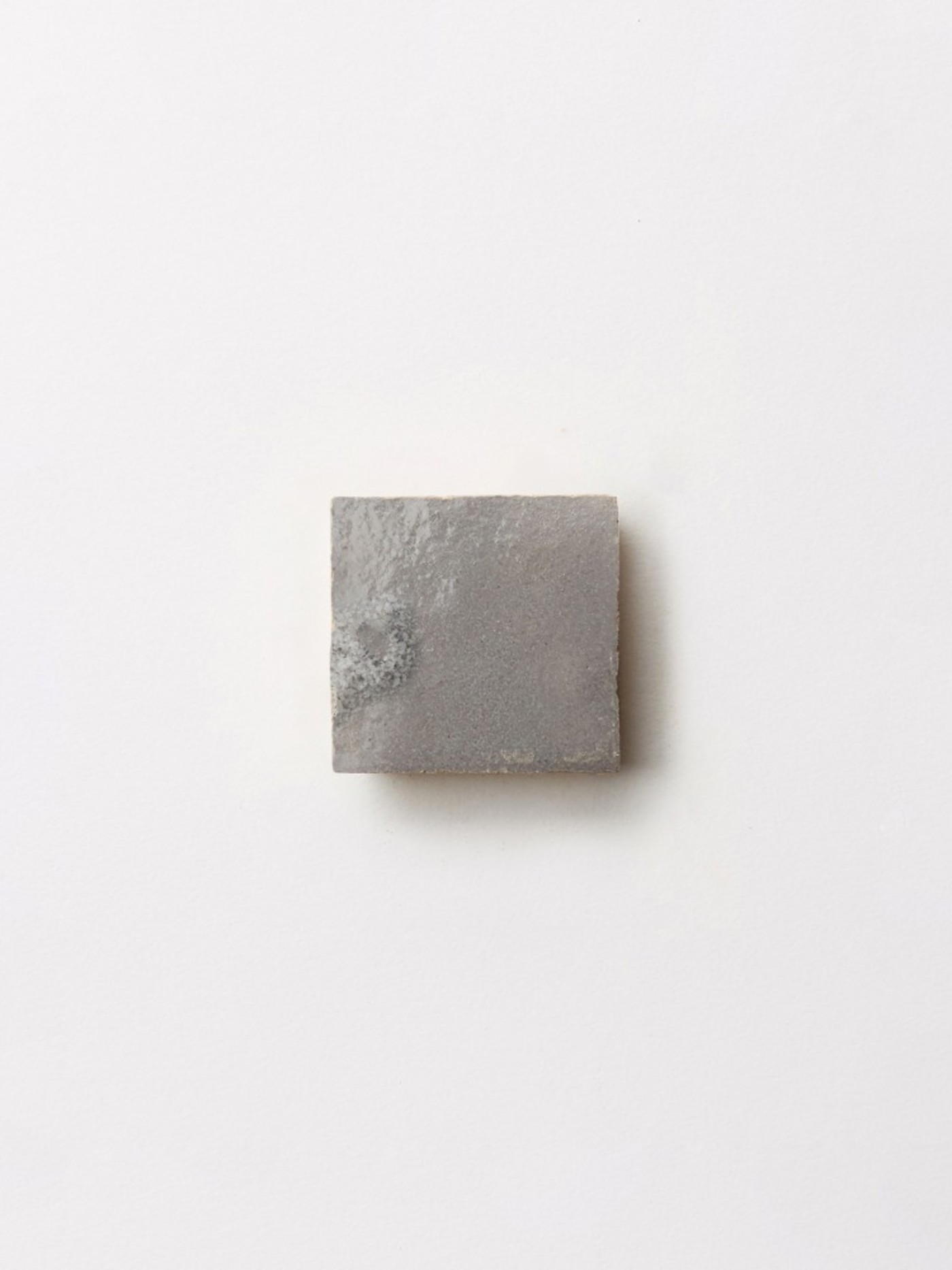 a grey square tile on a white background.