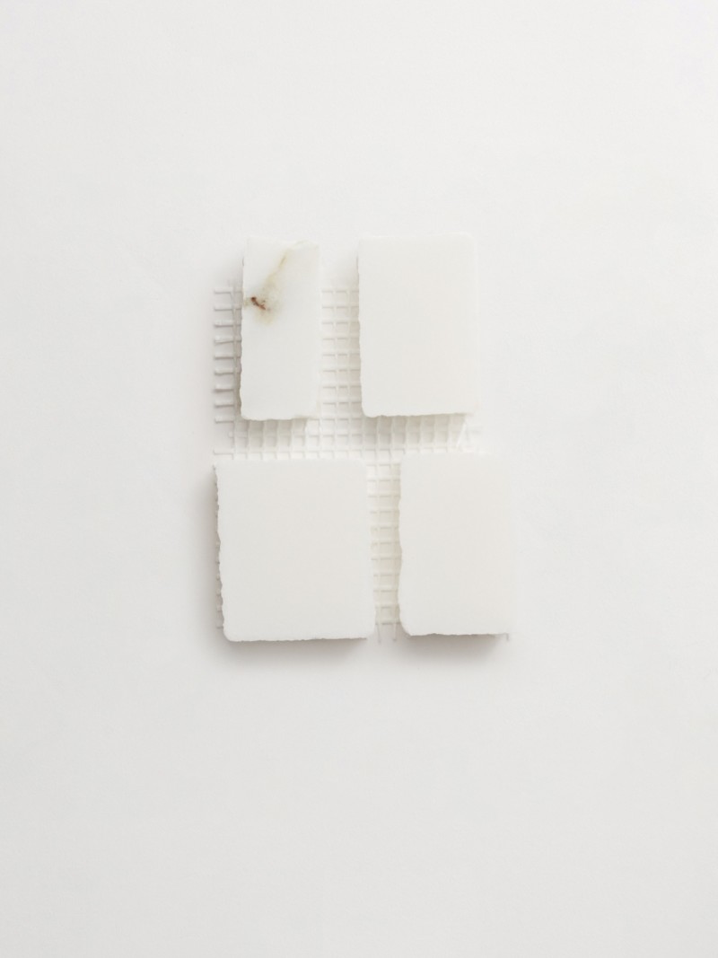 four pieces of white marble on a white surface.