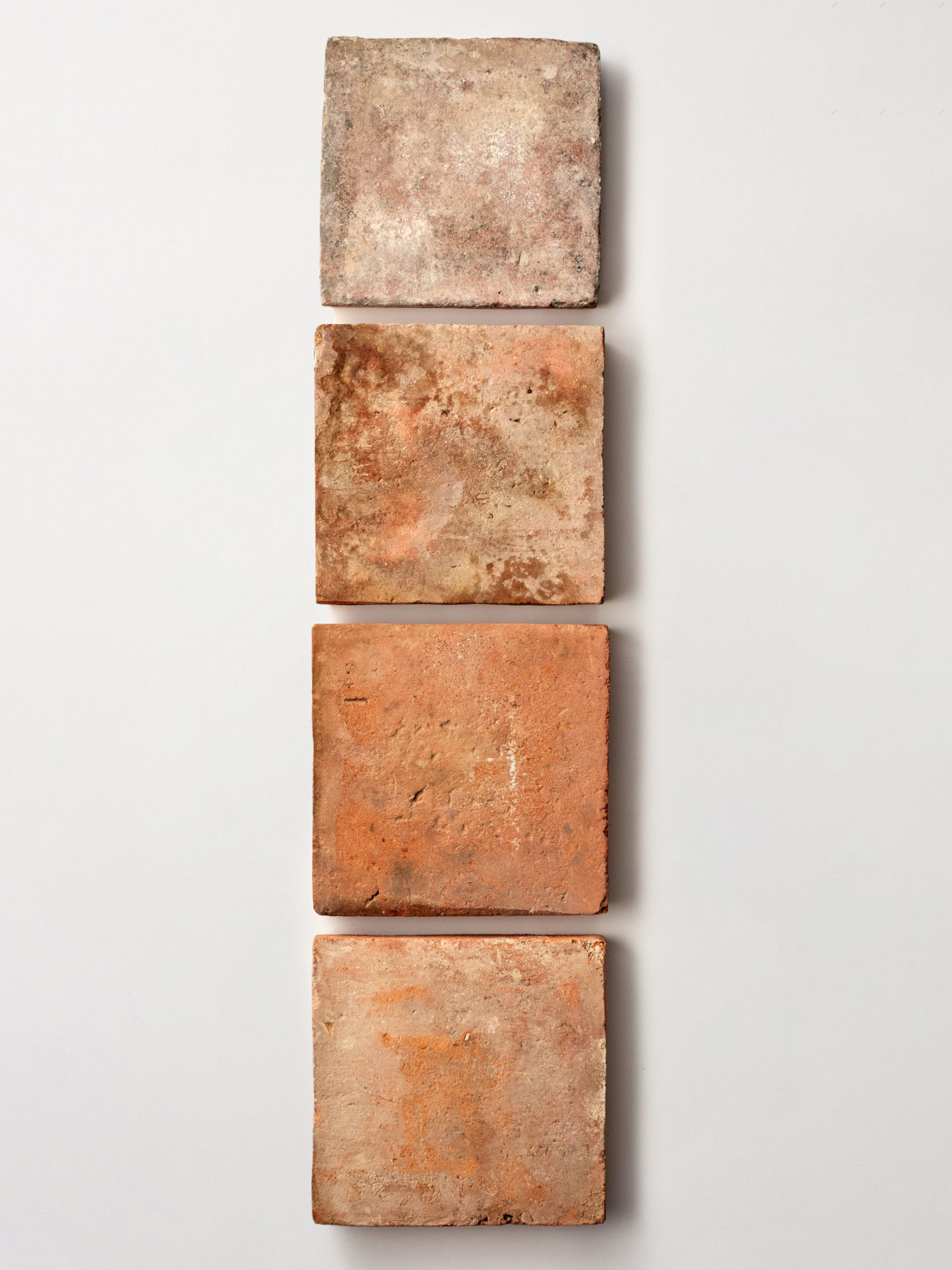 four terracotta tiles on a white background.