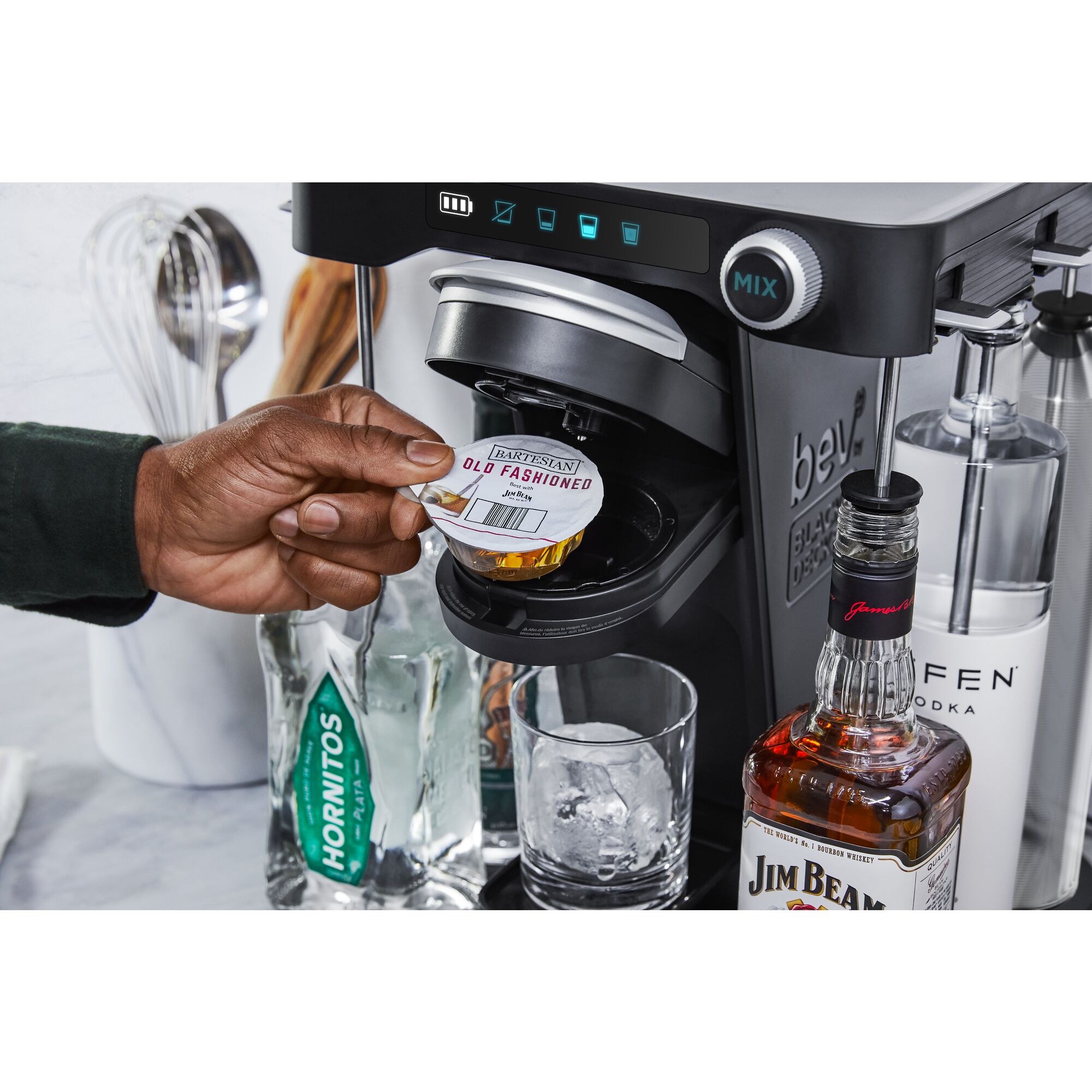 close-up, in the kitchen, of a man's hand inserting an old fashioned drink capsule into the bev by BLACK+DECKER™ cocktail maker