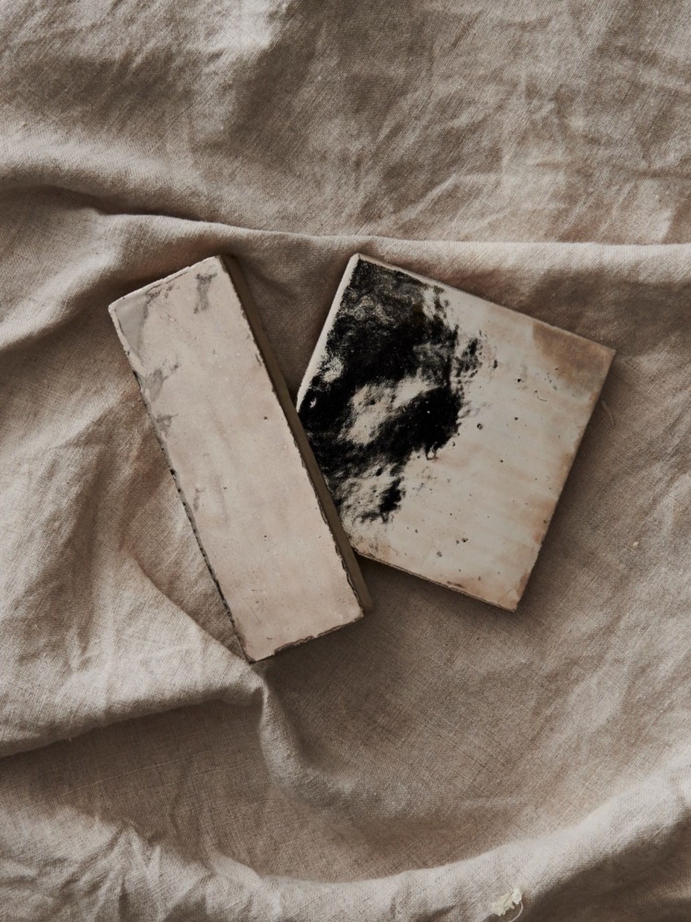 two pieces of tile on a beige cloth.