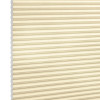 Beige honeycomb (cellular) blinds, fully lowered and closed, filtering soft light; exposed left edge shows hexagonal cell ends against a plain white background.